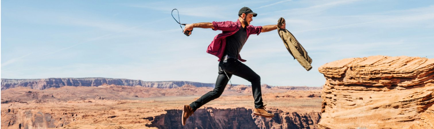 A motivated man jumping across a cavern