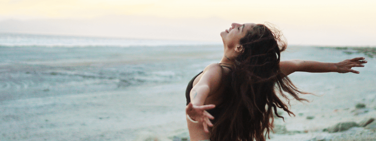 A woman looks relaxed and peaceful at the beach.